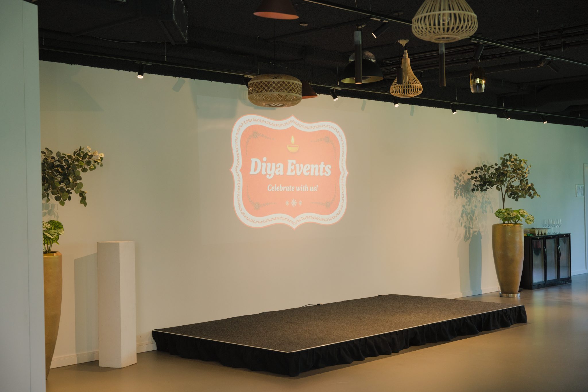 Podium met de Diya Events-projectie en planten aan weerszijden.