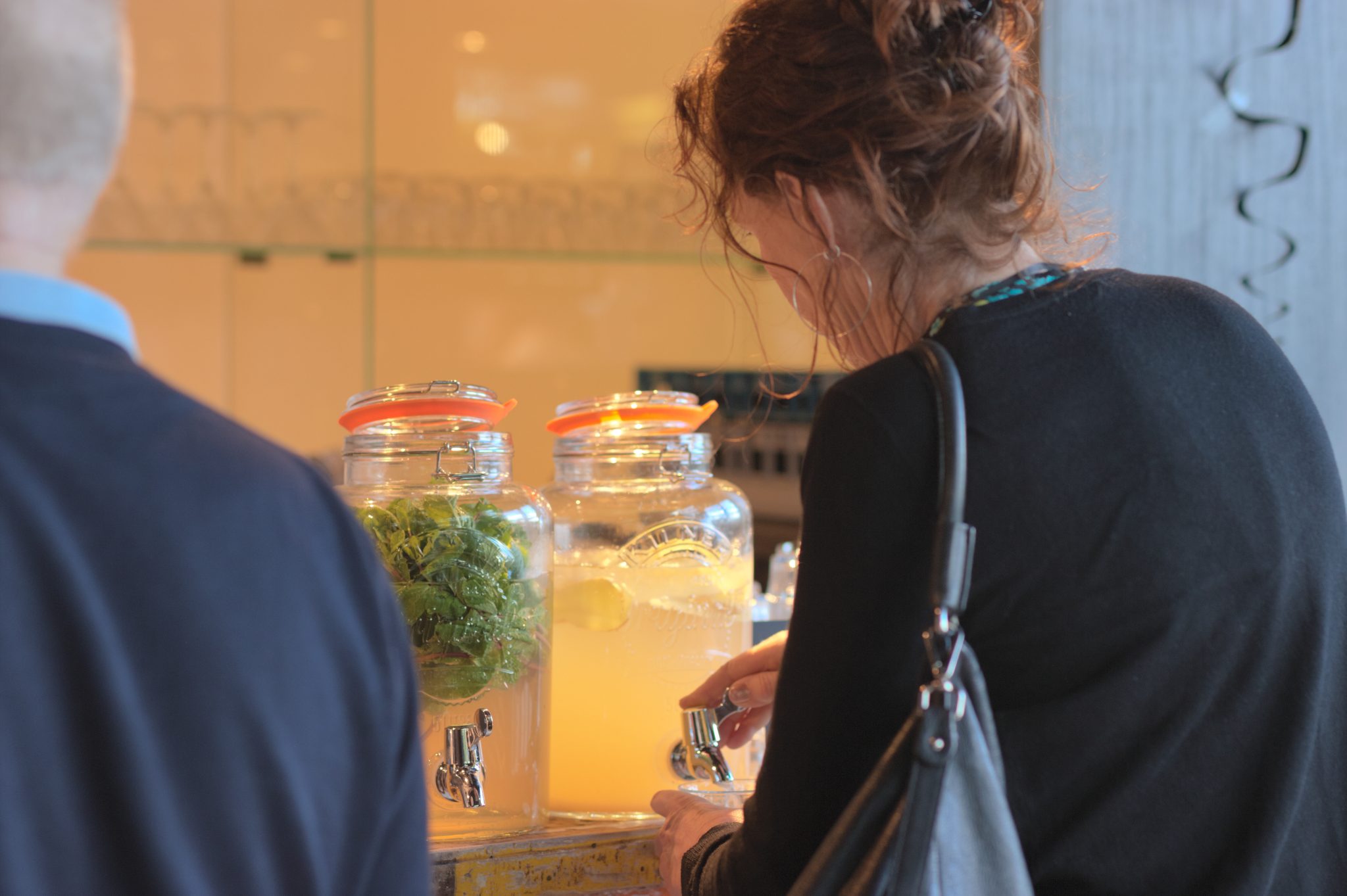 Gasten van achteren bij glazen dispensers met water, citroen en munt.