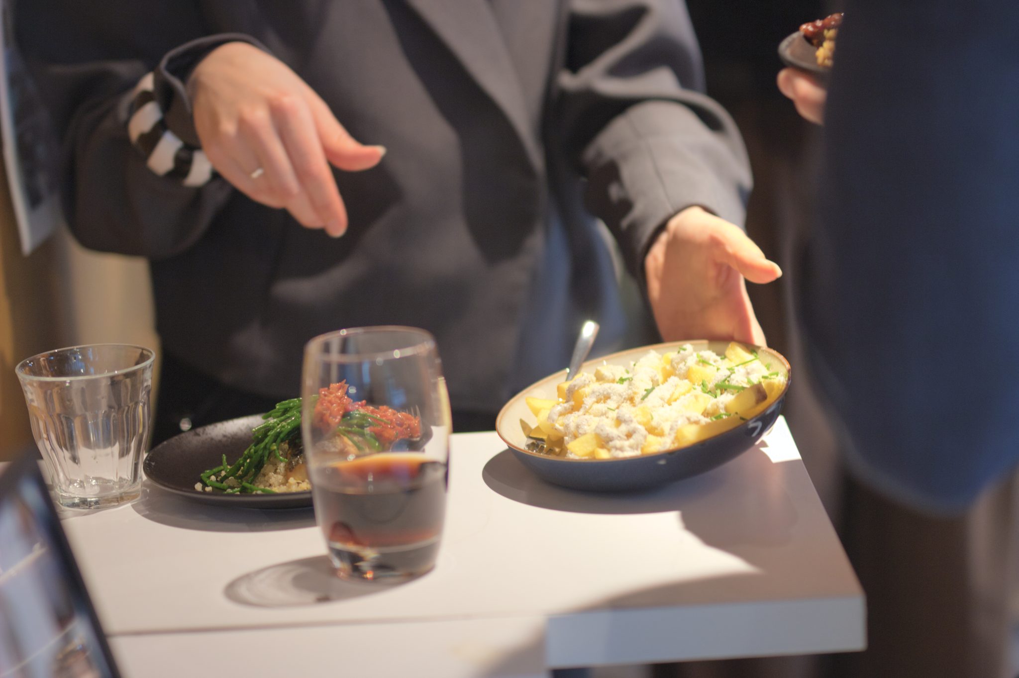 Handen rond vers geserveerde gerechten aan een lichte tafel.